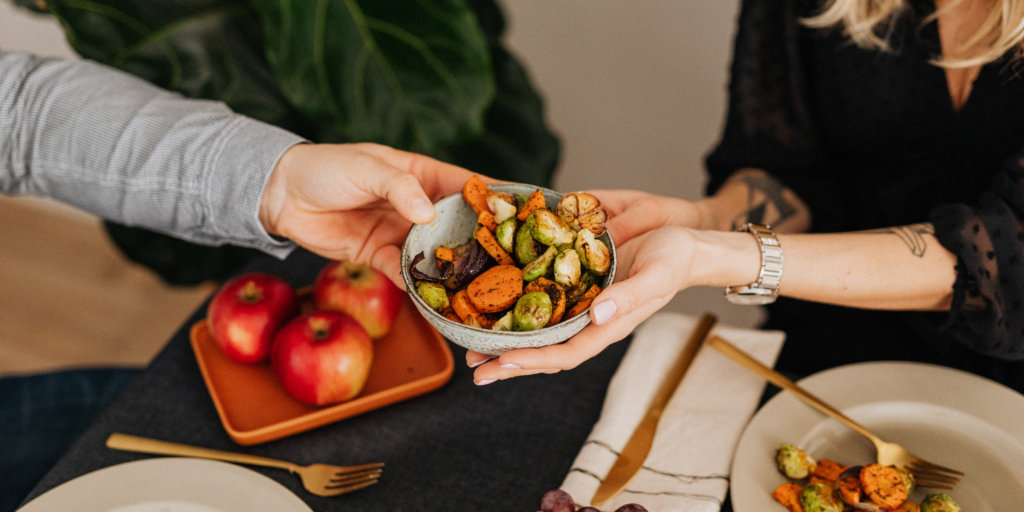 Hands passing bowl of roasted Brussels sprouts
